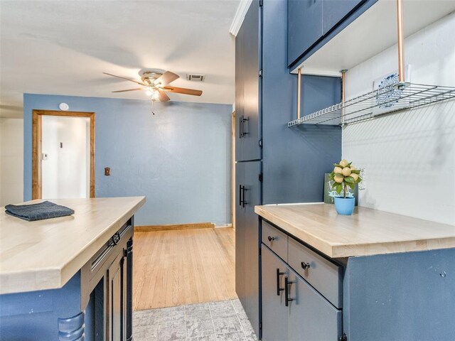 3208 NW 34th St, Oklahoma City, OK 73112 - kitchen with ceiling fan, baseboards, light countertops, light wood-style flooring, and blue cabinetry