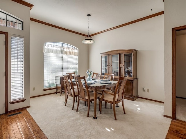 dining room featuring baseboards, ornamental molding, and light wood-style floors