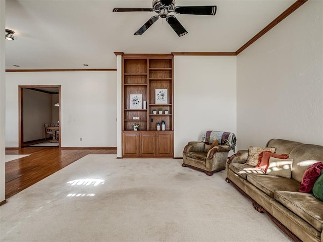 living room with ornamental molding, ceiling fan, light colored carpet, light wood-type flooring, and baseboards