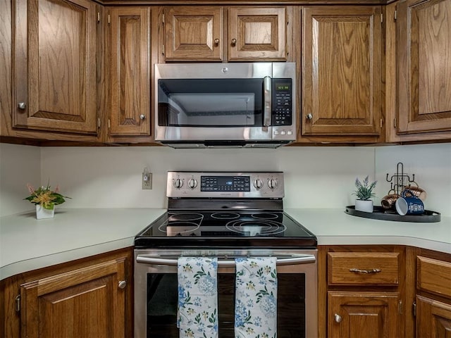 kitchen with stainless steel appliances, light countertops, and brown cabinetry