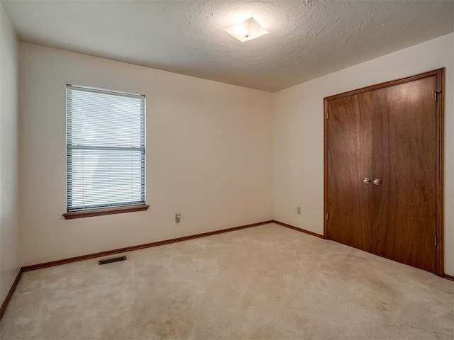 unfurnished bedroom featuring light colored carpet, baseboards, and a closet