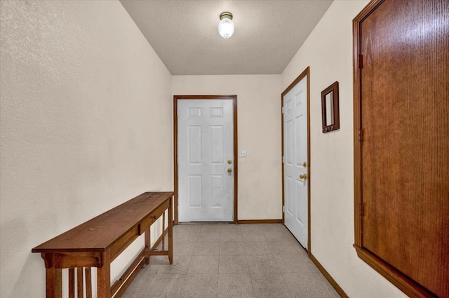 doorway with baseboards and a textured ceiling