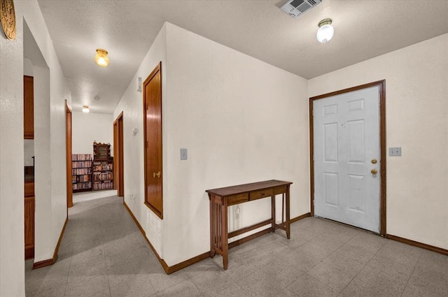 foyer entrance with a textured ceiling and baseboards