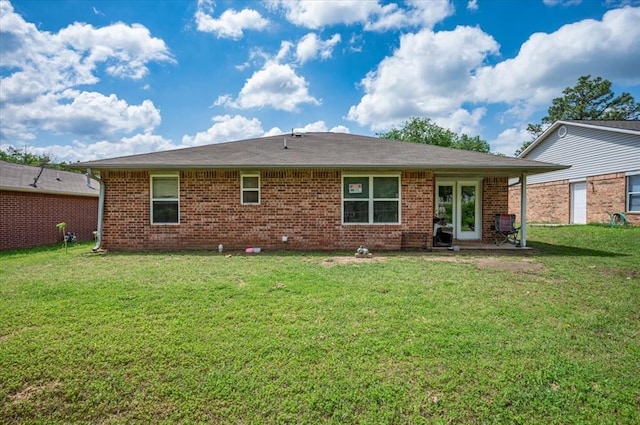 back of property featuring a yard and brick siding