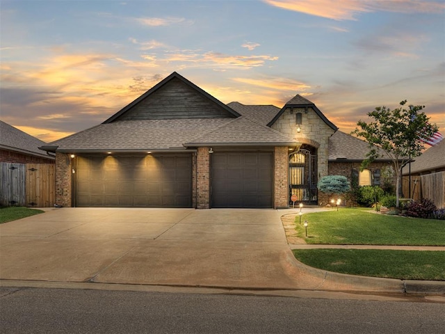 view of front of property featuring an attached garage, driveway, a shingled roof, brick siding, and stone siding