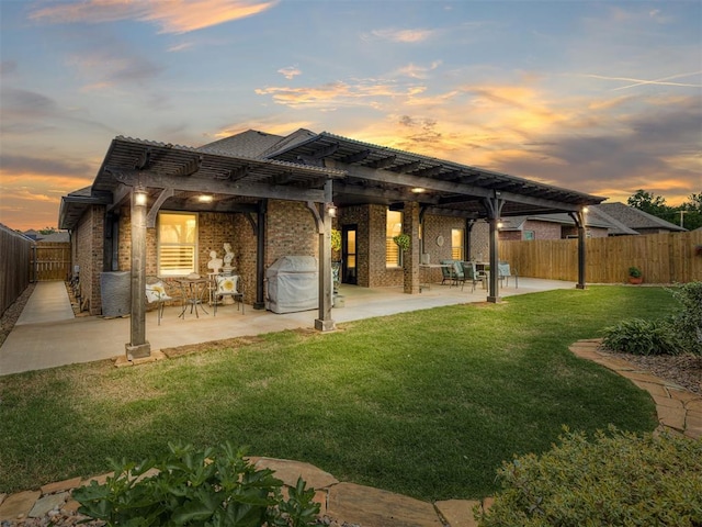 back of property at dusk featuring a pergola, brick siding, and a patio area