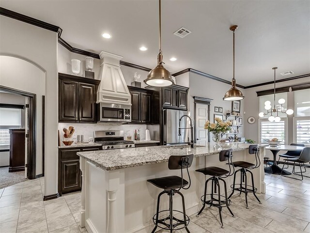 kitchen featuring stainless steel appliances, ornamental molding, a sink, a spacious island, and a kitchen breakfast bar