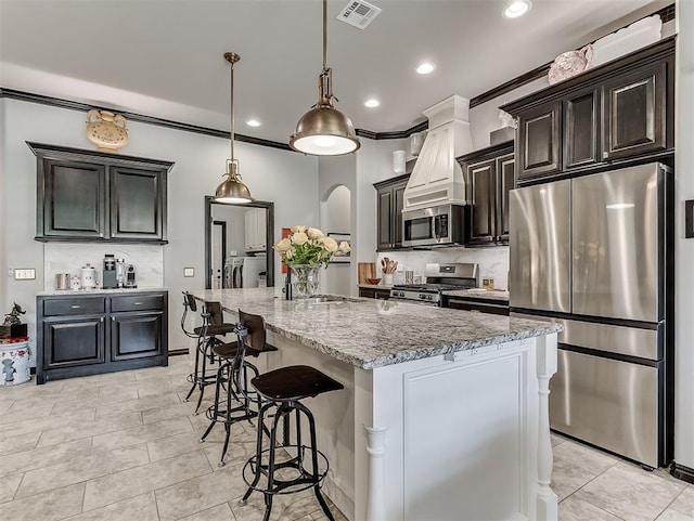 kitchen featuring stainless steel appliances, a sink, a kitchen breakfast bar, light stone counters, and recessed lighting