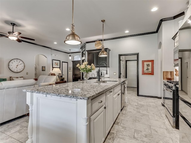 kitchen featuring arched walkways, range with gas stovetop, stainless steel dishwasher, open floor plan, and a ceiling fan