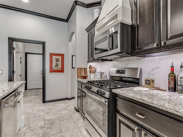 kitchen featuring appliances with stainless steel finishes, ornamental molding, tasteful backsplash, light stone countertops, and dark brown cabinets