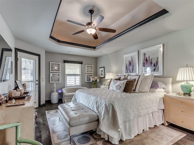 bedroom featuring a raised ceiling, wood finished floors, and a ceiling fan
