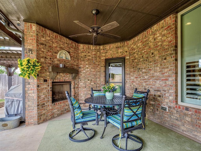 view of patio / terrace with an outdoor brick fireplace, a ceiling fan, and outdoor dining space