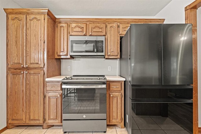 8109 Dawn Cir, Oklahoma City, OK 73135 - kitchen featuring appliances with stainless steel finishes, light tile patterned flooring, light countertops, and brown cabinets