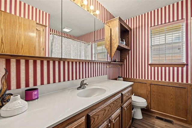 8109 Dawn Cir, Oklahoma City, OK 73135 - full bathroom featuring wallpapered walls, toilet, wood finished floors, a wainscoted wall, and vanity