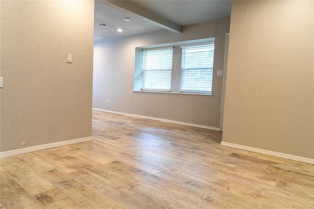 201 Lois Ave, Tuttle, OK 73089 - unfurnished room with light wood-style flooring, beam ceiling, baseboards, and a textured wall
