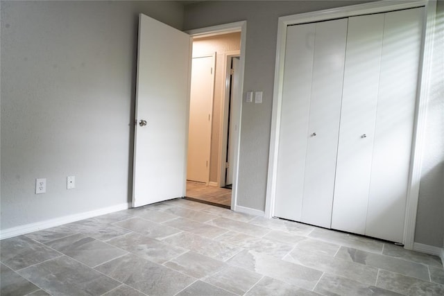 201 Lois Ave, Tuttle, OK 73089 - unfurnished bedroom featuring a closet, baseboards, and light stone finish floors