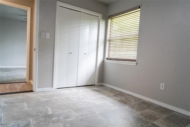 201 Lois Ave, Tuttle, OK 73089 - unfurnished bedroom featuring a closet, baseboards, multiple windows, and a textured wall