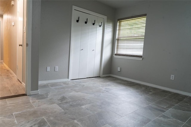 201 Lois Ave, Tuttle, OK 73089 - unfurnished bedroom with baseboards, a closet, and stone finish flooring