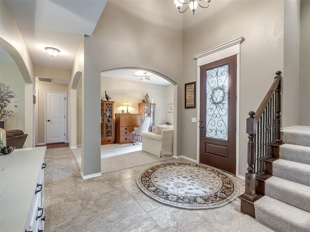 3570 Riverwood Ln, Edmond, OK 73034 - entryway with arched walkways, a chandelier, a towering ceiling, and baseboards