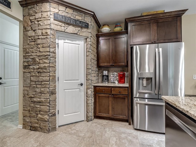3570 Riverwood Ln, Edmond, OK 73034 - kitchen featuring appliances with stainless steel finishes, light stone countertops, dark brown cabinetry, and crown molding