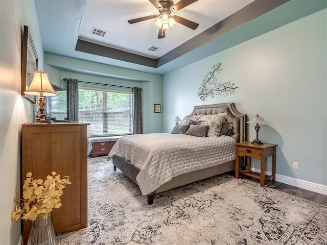 3570 Riverwood Ln, Edmond, OK 73034 - bedroom with wood finished floors, baseboards, a raised ceiling, and a ceiling fan