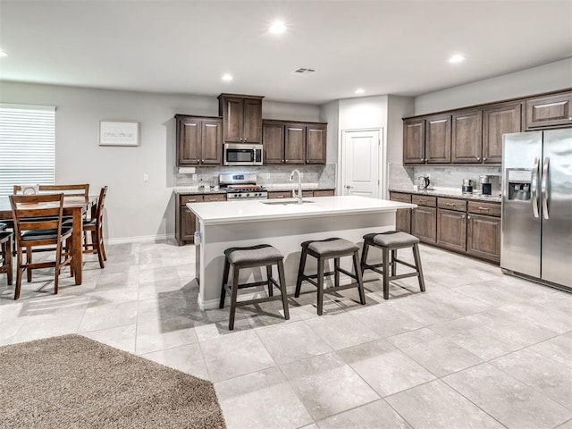 10301 NW 25th St, Yukon, OK 73099 - kitchen with stainless steel appliances, a sink, decorative backsplash, a kitchen bar, and dark brown cabinets