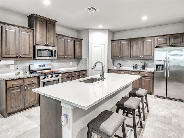 10301 NW 25th St, Yukon, OK 73099 - kitchen with appliances with stainless steel finishes, a sink, decorative backsplash, light countertops, and a kitchen breakfast bar