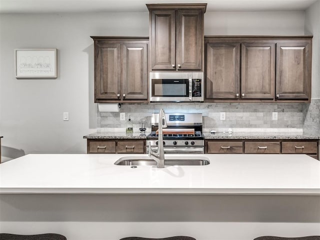 10301 NW 25th St, Yukon, OK 73099 - kitchen featuring stainless steel appliances, dark brown cabinetry, backsplash, and a breakfast bar