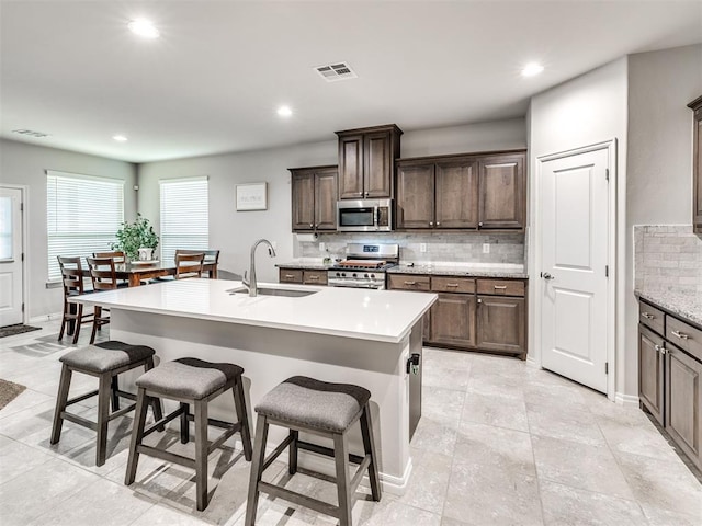 10301 NW 25th St, Yukon, OK 73099 - kitchen featuring stainless steel appliances, a sink, decorative backsplash, a breakfast bar, and recessed lighting