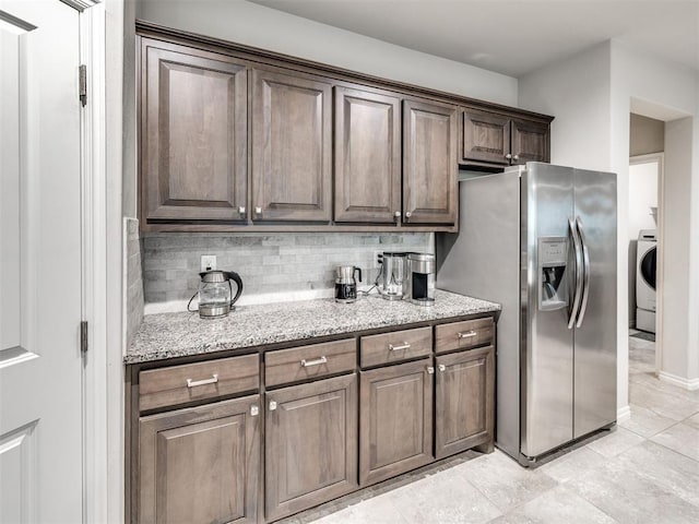 10301 NW 25th St, Yukon, OK 73099 - kitchen featuring stainless steel fridge with ice dispenser, washer / dryer, light stone countertops, and backsplash