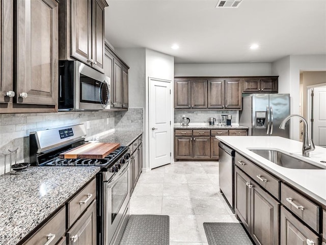 10301 NW 25th St, Yukon, OK 73099 - kitchen with appliances with stainless steel finishes, a sink, tasteful backsplash, dark brown cabinetry, and recessed lighting