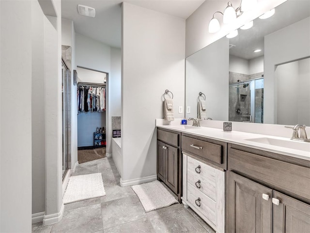 10301 NW 25th St, Yukon, OK 73099 - full bathroom featuring a stall shower, double vanity, baseboards, and a spacious closet