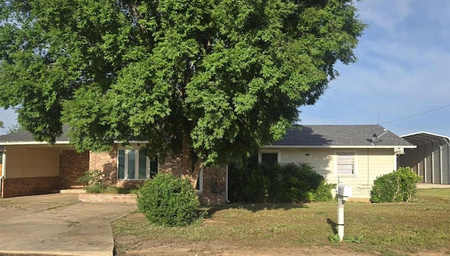 view of front of property featuring brick siding, driveway, a front lawn, and a carport