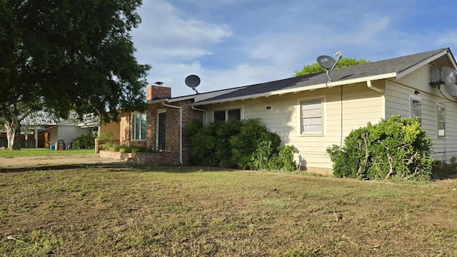 back of property featuring a chimney and a lawn