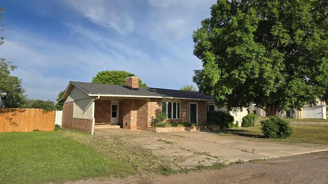 ranch-style house with brick siding, a chimney, and driveway