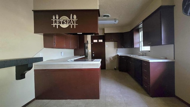 kitchen with a peninsula, black appliances, a sink, light countertops, and light tile patterned flooring