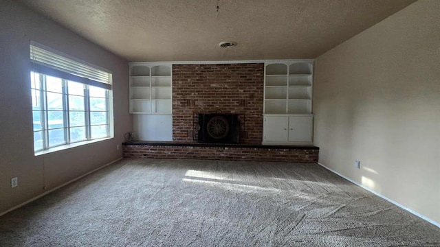 unfurnished living room featuring a textured ceiling, carpet, built in shelves, a brick fireplace, and baseboards