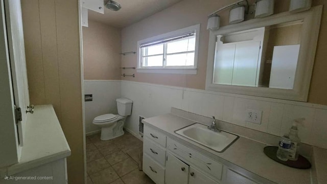 bathroom featuring wainscoting, toilet, vanity, and tile patterned floors