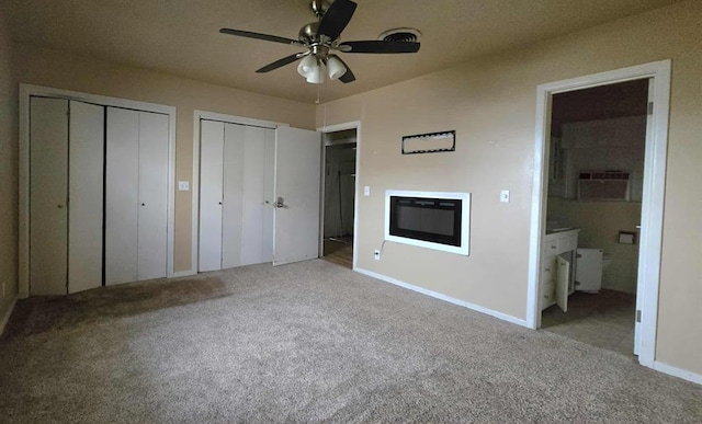 unfurnished bedroom with carpet flooring, multiple closets, connected bathroom, and baseboards