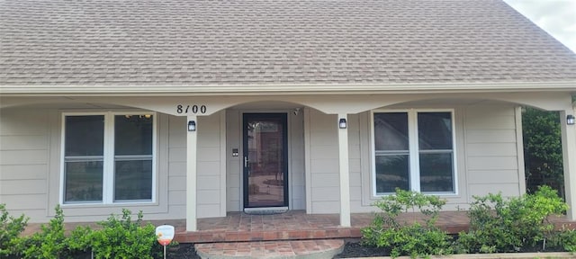 property entrance with roof with shingles and a porch