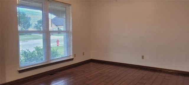 spare room with baseboards and dark wood finished floors