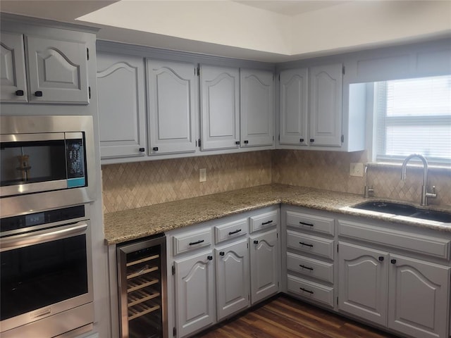 kitchen with appliances with stainless steel finishes, a sink, wine cooler, and decorative backsplash