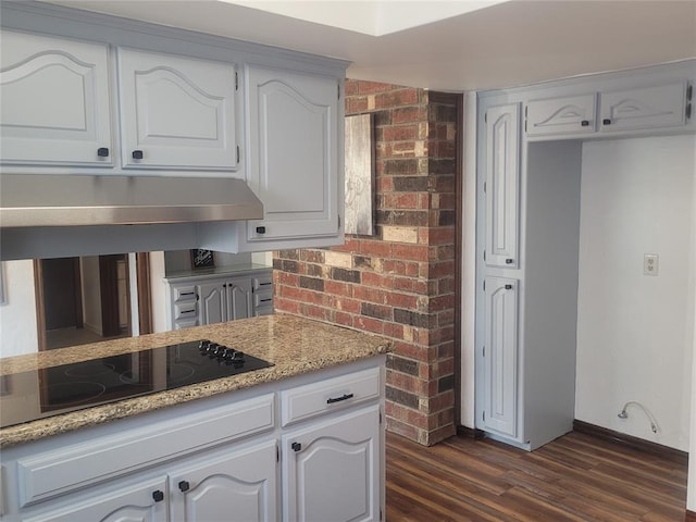 kitchen with black electric cooktop, dark wood finished floors, baseboards, under cabinet range hood, and light stone counters