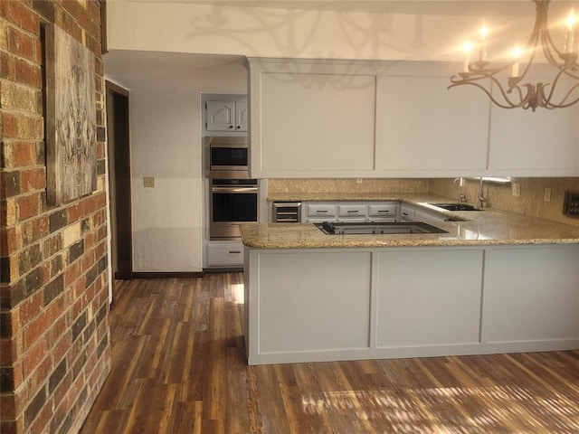 kitchen featuring appliances with stainless steel finishes, a sink, light stone countertops, dark wood-style floors, and white cabinetry