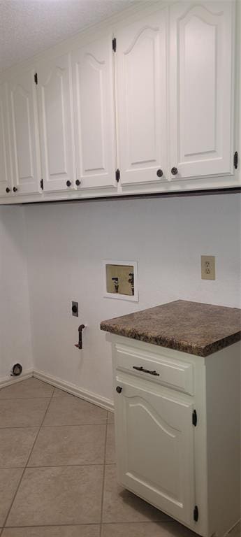 laundry area featuring cabinet space, washer hookup, light tile patterned floors, electric dryer hookup, and baseboards