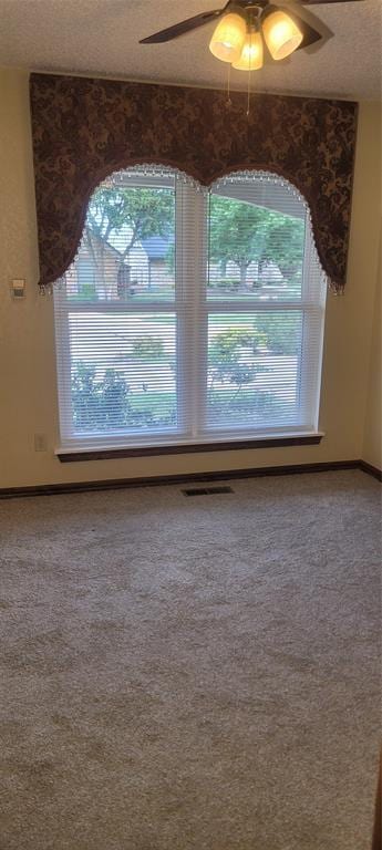 empty room featuring a ceiling fan, carpet, a textured ceiling, and baseboards