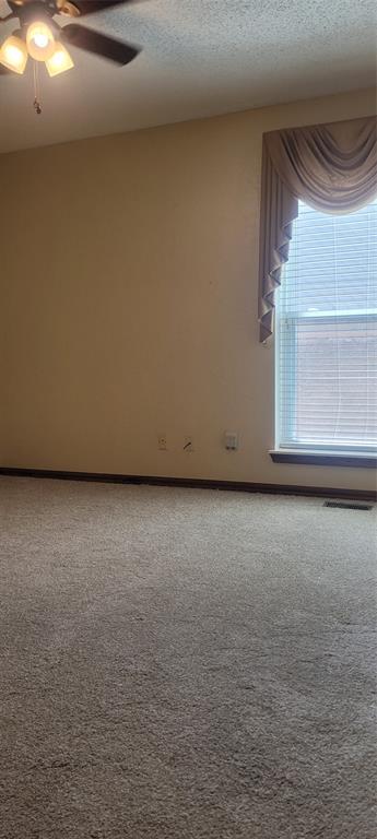 spare room with ceiling fan, a textured ceiling, and carpet floors