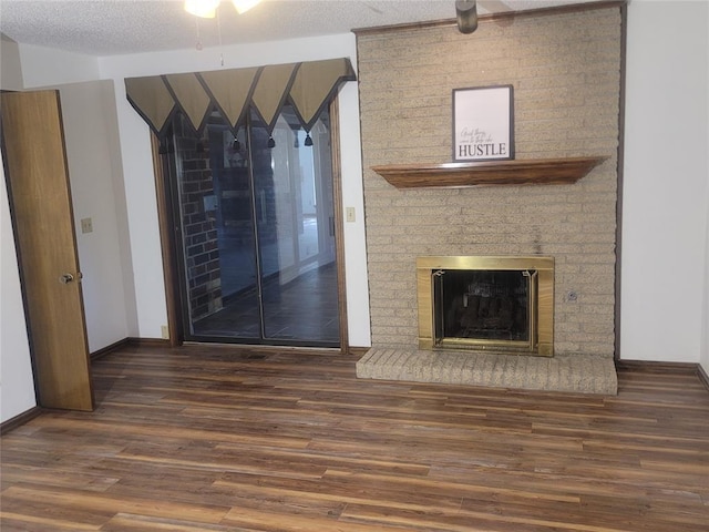 unfurnished living room featuring wood finished floors, a fireplace, baseboards, and a textured ceiling