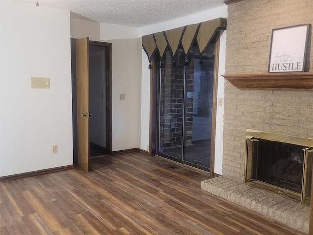 unfurnished living room featuring wood finished floors, baseboards, a textured ceiling, and a fireplace