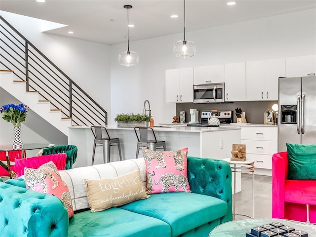 living area featuring finished concrete flooring, stairs, and recessed lighting